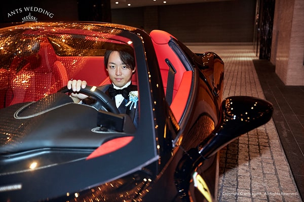スポーツカーに乗る新郎の写真